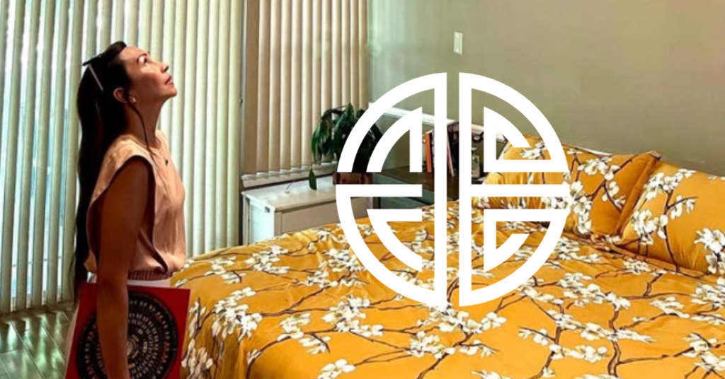 Person looking up in a bedroom with a bed covered in yellow floral bedding and vertical blinds.